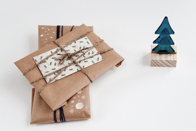 Photo arbre de noël et cadeaux en papier kraft simples cadeaux faits à la main et jouet en verre sur fond blanc salutations saisonnières espace pour le texte