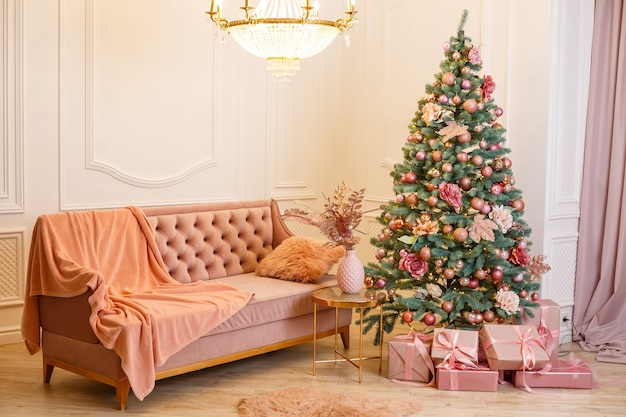 Arbre de Noël avec des cadeaux roses dans une salle de Noël blanche. Maison joliment décorée avec des jouets roses décorés d'arbres et de cadeaux pour Noël.