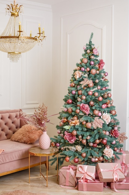 Arbre de Noël avec des cadeaux roses dans une salle de Noël blanche. Maison joliment décorée avec des jouets roses décorés d'arbres et de cadeaux pour Noël.