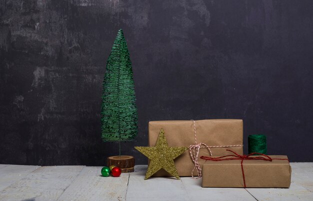 Arbre de Noël avec des coffrets cadeaux et étoiles sur une table en bois blanc vintage.