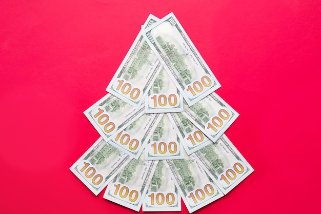 Arbre de Noël composé de billets de 100 dollars sur fond rouge. Décor de Noël sur le thème de la finance, de l'épargne, de la richesse, des dépenses du nouvel an. Catégoriquement. Pile de 100 $, Investissements, entreprise