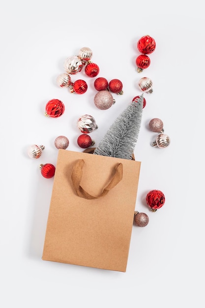 Arbre de Noël dans un sac cadeau artisanal, boules décoratives sur fond blanc. Vue de dessus, mise à plat.