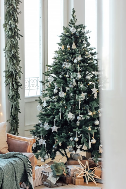 Arbre de Noël décoré avec des cadeaux dans le salon lumineux