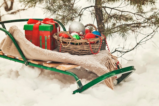 Arbre de Noël décoré dans une couverture de traîneaux de forêt enneigée et un panier de jouets à effet rétro
