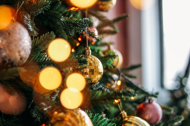 Arbre de Noël décoré dans des jouets or et violets avec le fond texturé de lumières bokeh