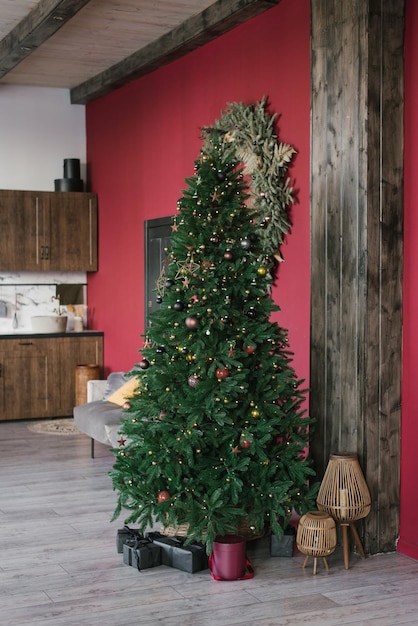 Arbre de Noël élégant avec des cadeaux en dessous dans un salon avec des murs en bordeaux