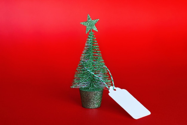 Arbre de Noël avec une étiquette sur fond rouge le concept de ventes et de remises de Noël