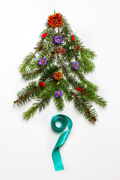 Photo arbre de noël fait de branches d'épinette et de fleurs de marguerite ruban turquoise sur fond blanc