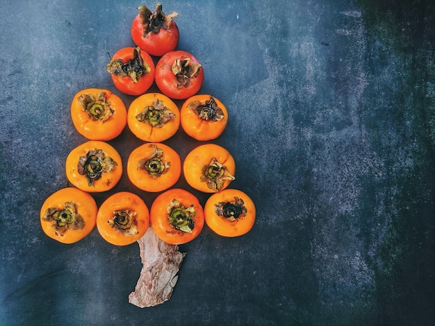 Arbre de Noël fait de fruits kaki sur fond sombre. Vue de dessus. Idée créative. Nourriture pour enfants