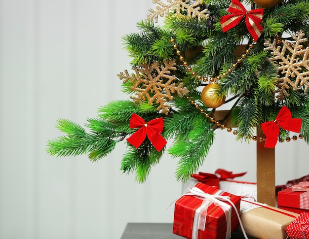 Un arbre de Noël fait main et des cadeaux sur fond de mur blanc, gros plan