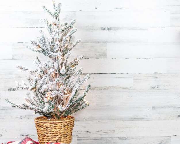 Photo arbre de noël floqué dans un panier sur fond de bois blanc avec place pour copie