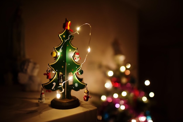 Arbre de Noël avec des guirlandes brillantes le soir à la maison.