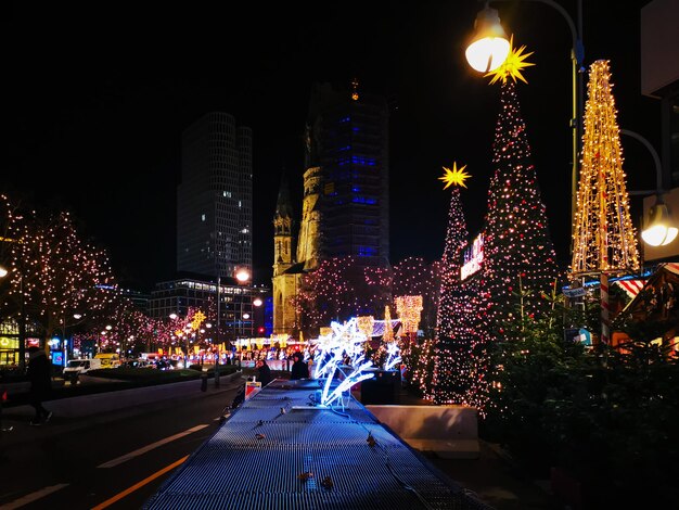 Photo arbre de noël illuminé contre les bâtiments la nuit