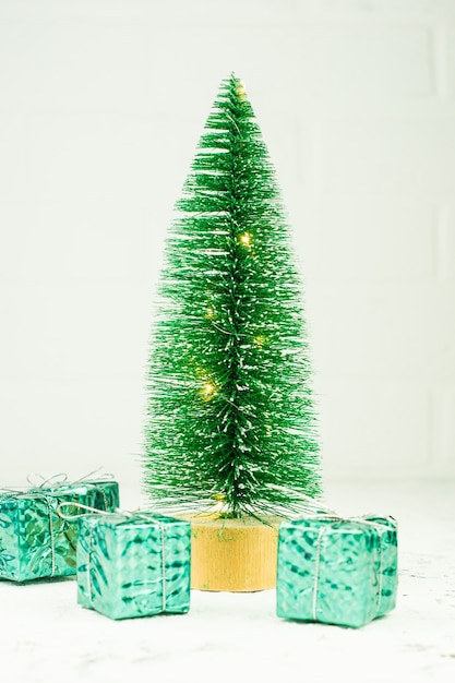 Photo arbre de noël miniature avec des coffrets cadeaux sur fond blanc. crd de voeux festif pour les vacances d'hiver.