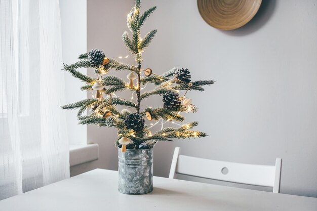 Arbre de Noël minimaliste réutilisable avec une guirlande en bois faite à la main en forme de champignons dans une pièce blanche