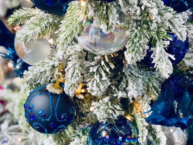 Un arbre de Noël avec des ornements bleus et de la neige sur les branches