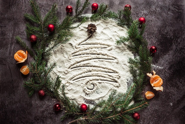 Arbre de Noël peint sur de la farine dans un cercle de branches d'épinette et de mandarine 1