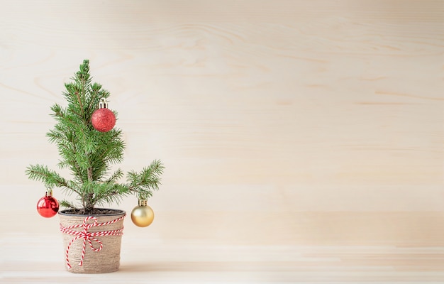 Arbre de Noël en pot de fleurs avec des ornements de Noël sur fond de bois