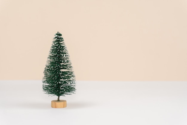 Arbre vert décoratif de Noël sur la table blanche et le mur de pêche pastel