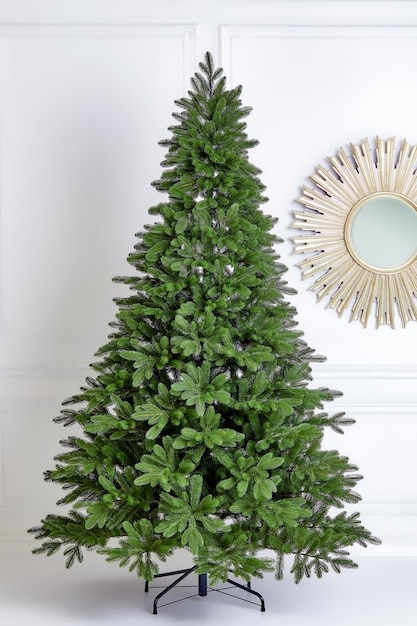 Arbre vert de Noël artificiel sans décorations sur un support métallique isolé sur fond blanc