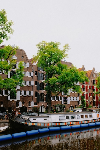 Photo des arbres et des bâtiments près de barge on canal à amsterdam