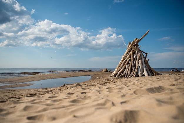 Arbres et branches légers empilés au bord de la mer comme un wigwam ou un paysage naturel de feu de joie en lettonie c