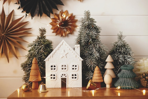 Arbres de petite maison de noël élégants lumières dorées sur fond d'étoiles en papier sur un mur en bois