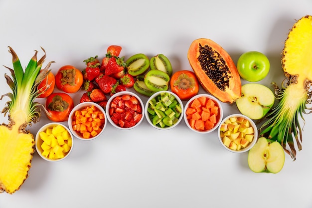 Arc-en-ciel de fruits exotiques et tropicaux papaye, ananas, kiwi, pomme, fraise et kaki. Hacher les fruits en cubes pour la salade.