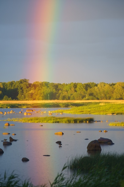 Arc-en-ciel sur le littoral pierreux au coucher du soleil