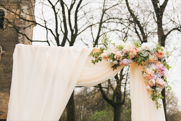 Photo arc de mariage décoré de tissu et de fleurs à l'extérieur. beau mariage mis en place. cérémonie de mariage sur pelouse verte dans le jardin.