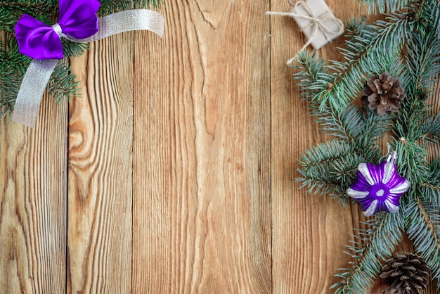 Arc et ruban violet décoratif. Composition de Noël avec des branches de sapin. cônes, perles et boules sur planche de bois avec espace copie.