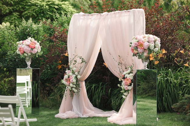 Arche et chaises pour la cérémonie de mariage, décorées de tissus et de compositions florales