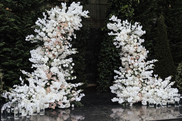 Une arche de mariage blanche avec des fleurs blanches et des bougies