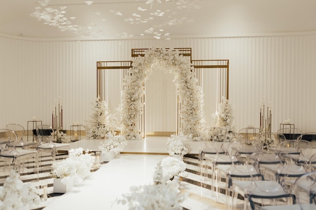 Photo arche de mariage décorée de fleurs blanches se tenant au centre de la cérémonie de mariage dans la résidence de luxe