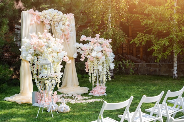 Arche de mariage décorée de tissu et de fleurs à l'extérieur