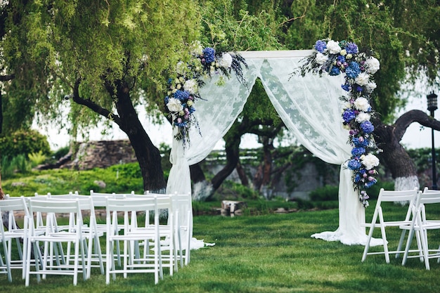 L'arche de mariage est décorée de tissu et de fleurs, des chaises pour les invités. Cérémonie de mariage dans la nature.