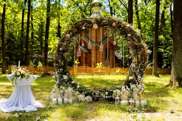 Arche pour la cérémonie de mariage Décorée de fleurs en tissu et de verdure Est située dans une forêt de pins Église de fond Décorations de mariage de style rustique Décor de mariage Just married