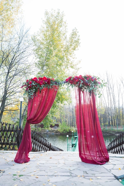 L'arche pour la cérémonie de mariage, décorée de fleurs en tissu et de verdure, se trouve dans une forêt de pins