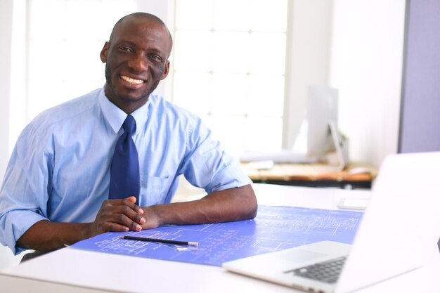 Architecte afro-américain travaillant avec un ordinateur et des plans au bureau