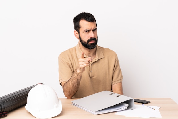 Architecte caucasien homme à barbe dans une table frustré et pointant vers l'avant