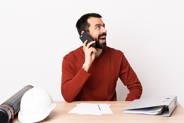 Architecte caucasien homme avec barbe dans une table en gardant une conversation avec le téléphone mobile