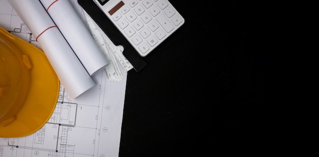 l'architecte a conçu le bâtiment dans le bureau d'études, le plan d'étage avec des catalogues de matériaux décoratifs et d'autres accessoires sur la table en bois noir.