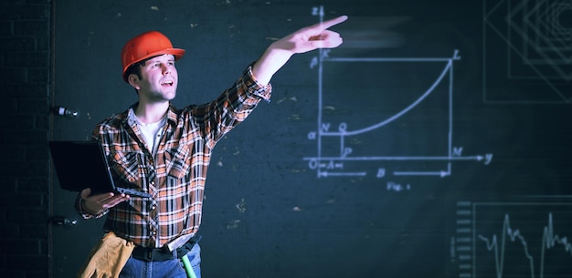 Architecte constructeur masculin dans un casque de protection et avec des papiers dans les mainsxA