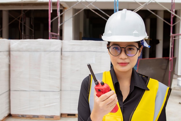 Architecte féminine asiatique professionnelle tenant un bâtiment de chantier de construction de talkie-walkie