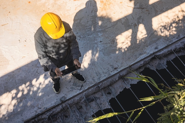 Architecte ou ingénieur civil avec casque sur le chantier de construction, vérification du calendrier sur tablette