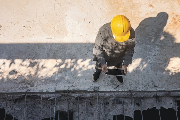 Architecte ou ingénieur civil avec casque sur le chantier de construction, vérification du calendrier sur tablette