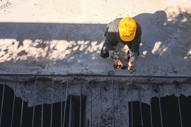 Architecte ou ingénieur civil avec casque sur le chantier de construction, vérification du calendrier sur tablette