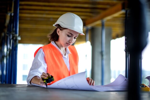 Architecte ou ingénieur travaillant, parcourant le projet de construction à l'intérieur du chantier de construction avec plan directeur. Femme ingénieurs en construction ou architectes qui travaillent.