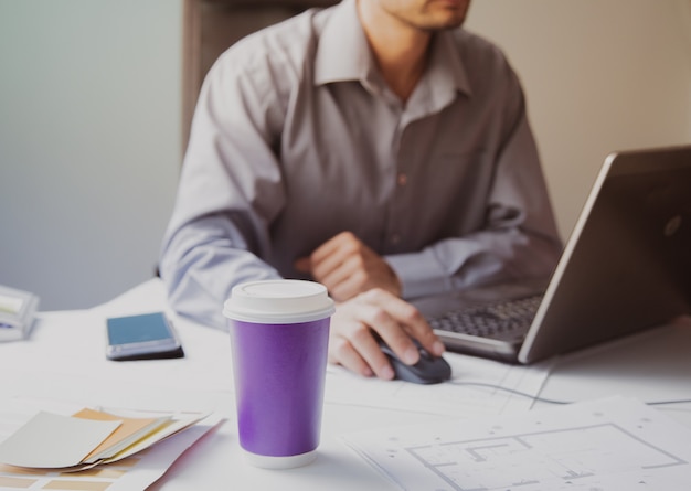 Architecte d'intérieur dans un environnement de travail Dessins et café avec un téléphone portable