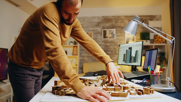 Architecte réussi parlant au téléphone tout en construisant un modèle de ville dans son bureau à domicile.